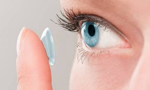 Woman inserting a contact lens in her eye.